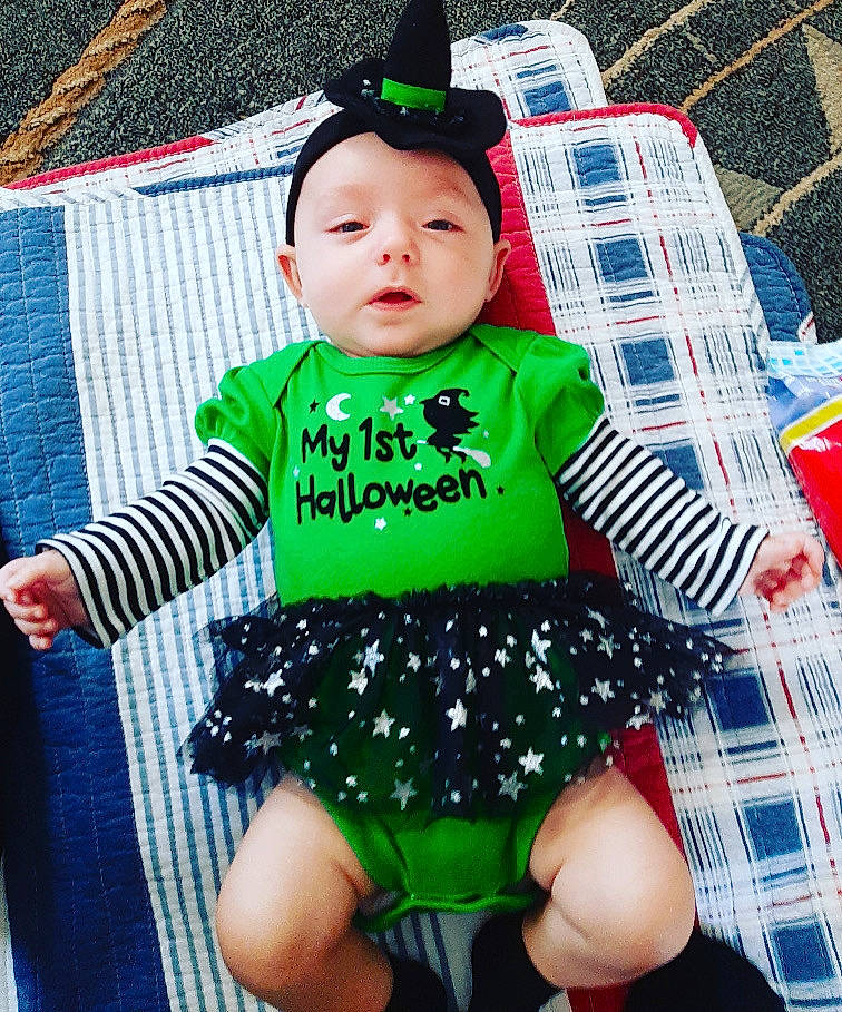 Frances is registered to the contest to win money with this photo: baby, baby_toddler_clothing, cap, child, costume_hat, fashion_accessory, green, happy, hat, headgear, headwear, holiday, human_leg, knee, pattern, person, sleeve, sun_hat, t_shirt, thigh