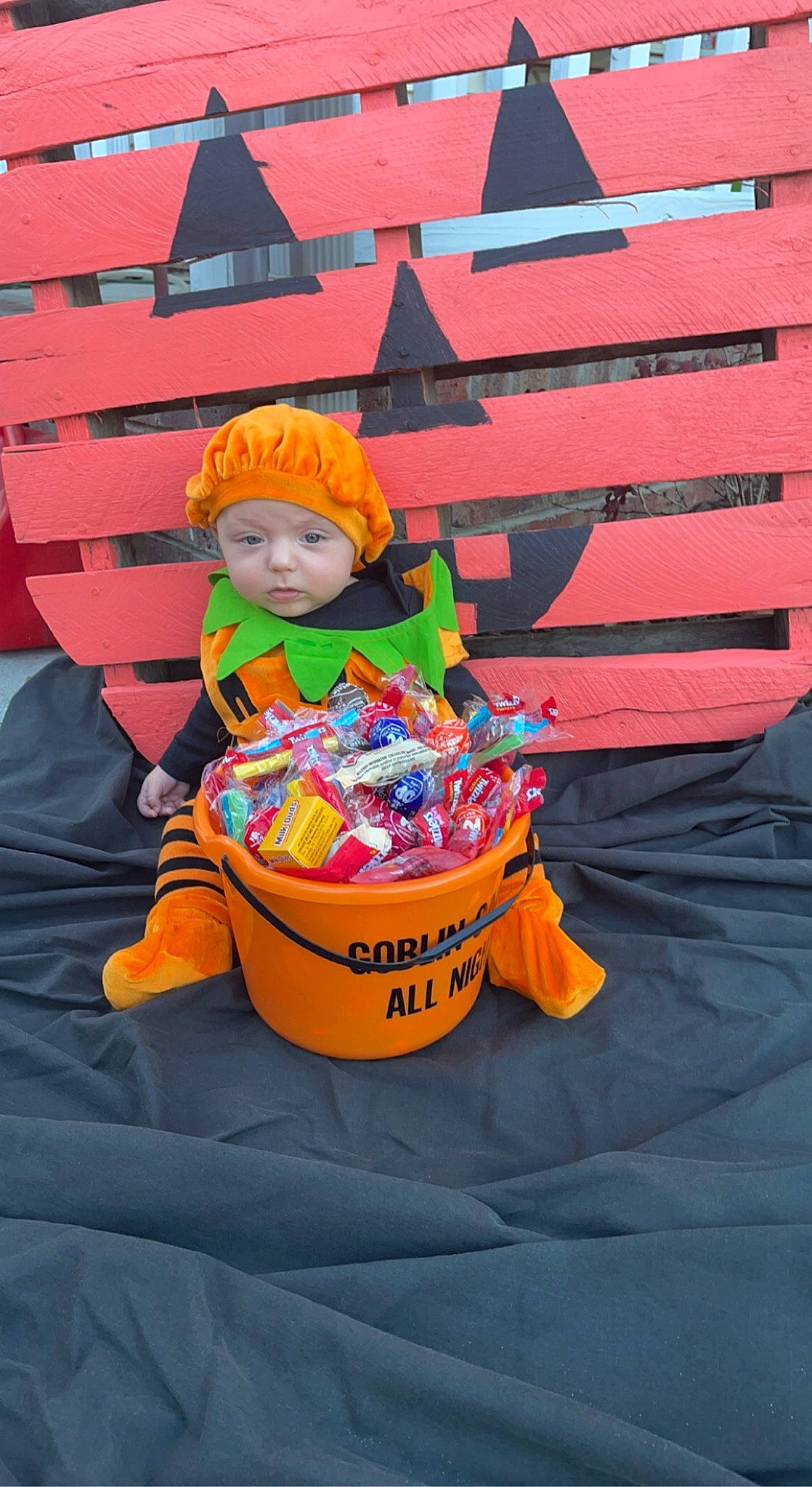 Frances is registered to the contest to win money with this photo: baby, baby_carriage, baby_products, bag, child, costume, event, fun, headwear, leisure, orange, person, personal_protective_equipment, recreation, red, sitting, toddler, toy, travel, wheel
