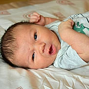 Uriah joined the competition — help win amazing prizes! baby, newborn, infant, lying_down, bed, bedding, onesie, dinosaur_print, curious, face, skin, arm, hand, sleepwear, indoors, child, person, cute, young, portrait