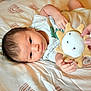 Uriah joined the competition — help win amazing prizes! baby, infant, child, bed, blanket, toy, plush, hand, person, soft_lighting, patterned_bed_sheet, cute, indoor, reaching, lying_down, clothing, skin, face, expression, newborn