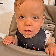 Malo participe au concours pour gagner de l'argent avec cette photo : bib, child, close_up, clothing, curious, expression, eyes, face, feeding, hair, hand, high_chair, indoor, mouth, person, seat, skin, table, toddler, young_child