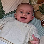 Ezio participe au concours pour gagner de l'argent avec cette photo : baby, smiling, infant, blanket, plush_toy, cozy, clothing, sweater, face, happy, child, lying_down, indoors, cute, soft_texture, portrait, young_child, furniture, home, playtime