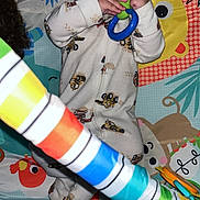 Axel joined the competition — help win amazing prizes! baby, infant, toy, play_mat, onesie, rattle, colorful, striped_toy, hardwood_floor, flash, red_eye, lying_down, hands, wide_eyes, teething_toy, cartoon_pattern, play_gym, cute, cozy, pajamas