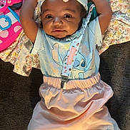 Damiyah is registered to the contest to win money with this photo: baby, child, infant, pink_bow, mittens, floral_blanket, stitch_character, pastel_clothing, toy, lying_down, white_socks, cute, smiling, indoor, soft_lighting, headband, playful, colorful, portrait, happy
