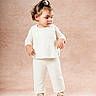 Everly joined the competition — help win amazing prizes! beige_background, child, curly_hair, cute, fashion, footwear, full_body, indoors, knitwear, looking_away, person, portrait, sandals, scrunchie, soft_lighting, standing, studio_photo, toddler, white_clothing, young_child