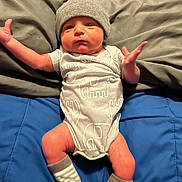 Cooper is registered to the contest to win money with this photo: baby, newborn, infant, hat, socks, blanket, blue_blanket, grey_blanket, clothing, lying_down, baby_girl, baby_boy, cute, face, human, skin, small, person, indoors, portrait