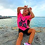 child, girl, pink_shirt, good_vibes, rocky_shore, water, sea, sky, clouds, sneakers, playful, outdoor, casual, summer, fun, posing, nature, coast, long_hair, happy