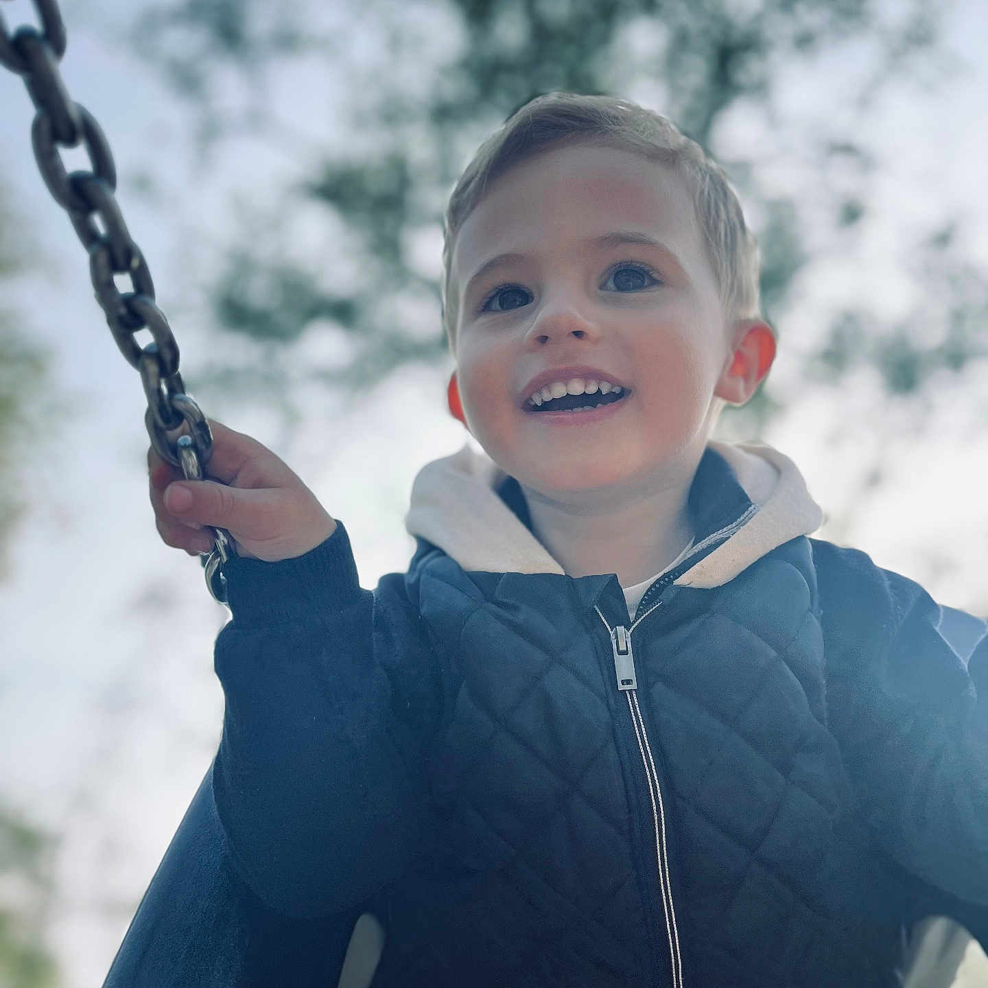 Maël a rejoint le concours — aidez-le/la à gagner de superbes lots ! activity, boy, casual_clothing, chain, child, daylight, face, fun, happy, hoodie, jacket, nature, outdoor, person, playground, portrait, smiling, swing, tree, young