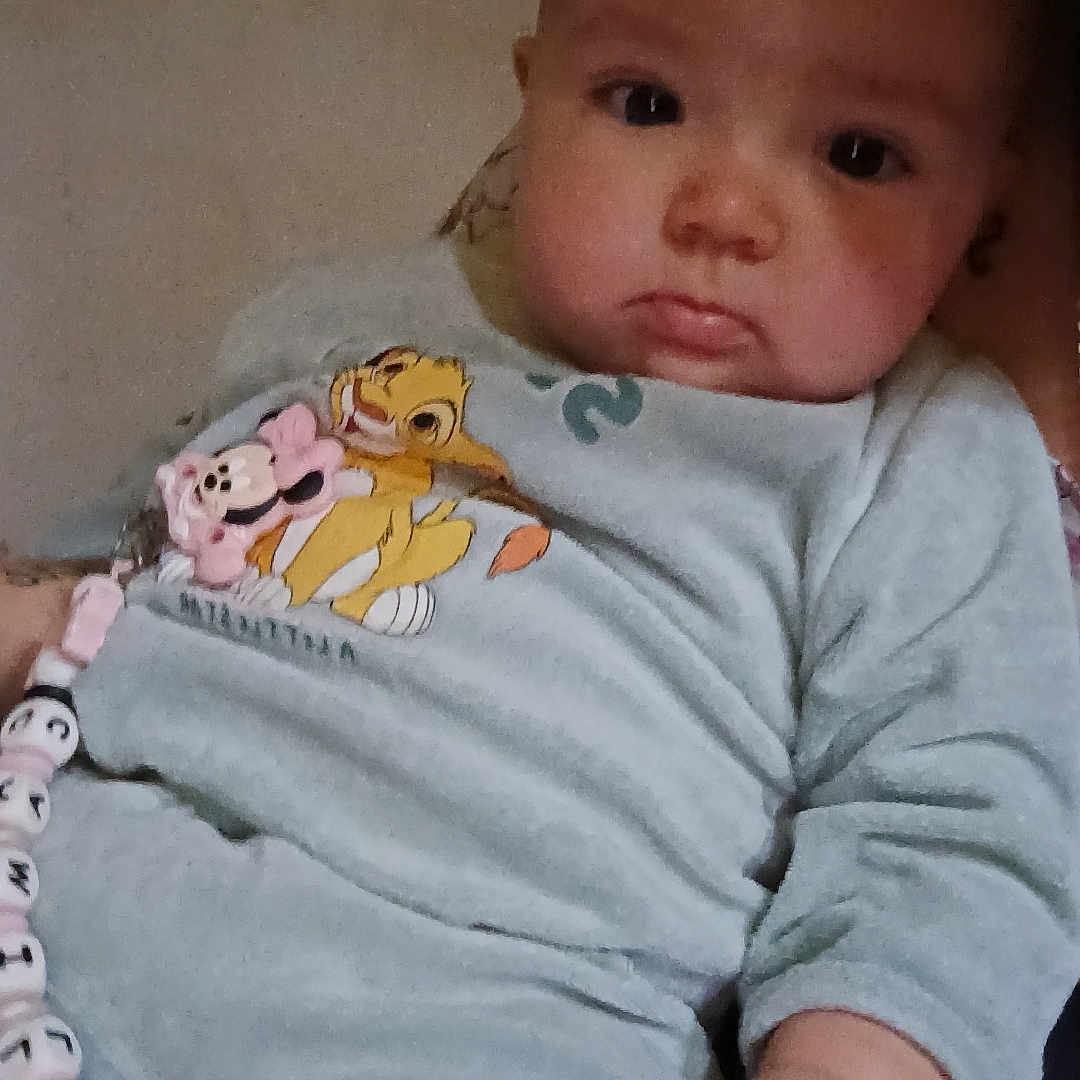 Camilya a rejoint le concours — aidez-le/la à gagner de superbes lots ! baby, beads, cartoon_print, child, clothing, cute, expression, face, hand, indoor, infant, looking, onesie, pacifier_clip, person, portrait, skin, sleeves, soft, young