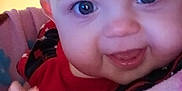 Blakely joined the competition — help win amazing prizes! baby, blanket, blue_eyes, child, closeup, cozy, cute, face, hand, happy, indoor, infant, lamp, monkey_pattern, person, pink_blanket, red_clothing, smile, soft_texture, warm_lighting