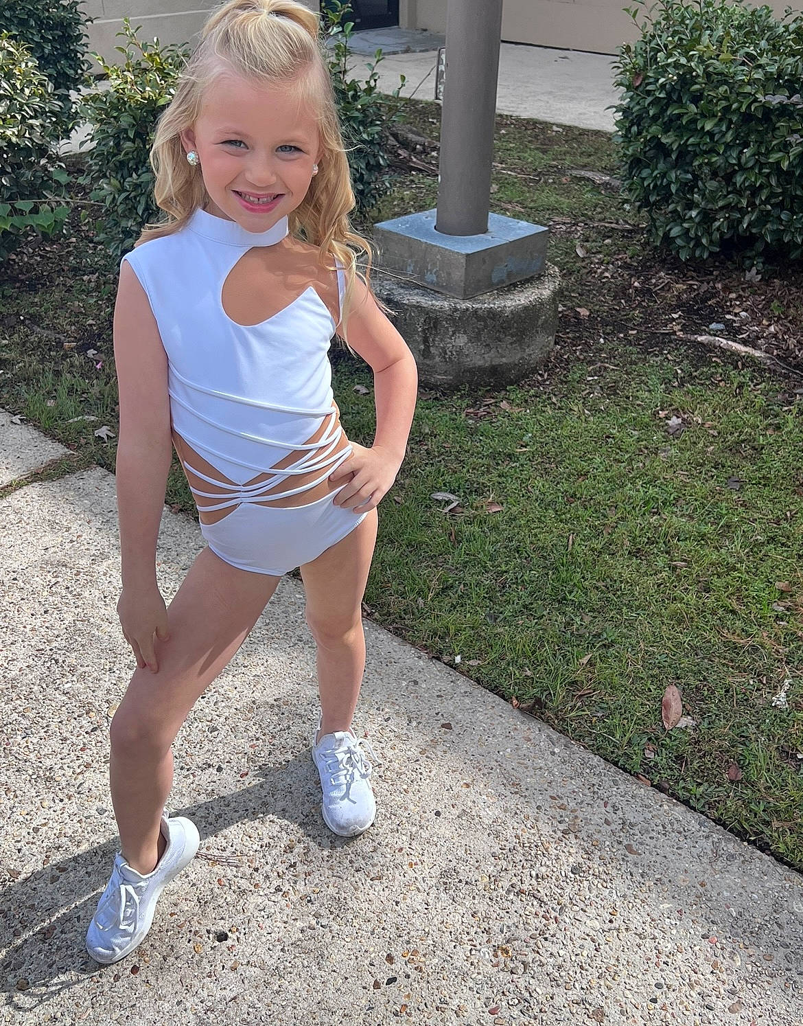 Kinley is registered to the contest to win money with this photo: asphalt, blond, calf, child, electric_blue, face, grass, hair, happy, human_leg, joy, knee, leisure, person, plant, shorts, smile, sportswear, thigh, toddler