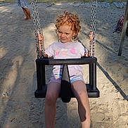 Lou-ann participe au concours pour gagner de l'argent avec cette photo : child, swing, playground, sand, river, water, summer, outdoor, trees, person, barefoot, shorts, tshirt, chains, smile, curly_hair, daylight, recreation, fun, park