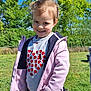 Lou-ann participe au concours pour gagner de l'argent avec cette photo : child, smiling, outdoor, grass, trees, blue_sky, jacket, sweater, hearts, happy, person, nature, sunny_day, casual_clothing, young_child, portrait, playful, greenery, daylight, cute