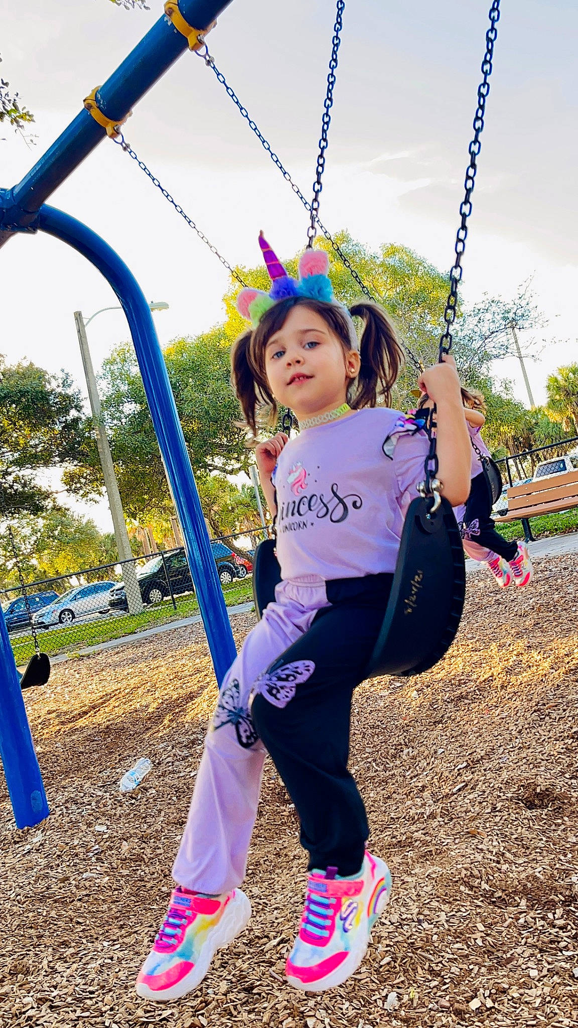 Valeria is registered to the contest to win money with this photo: blue, child, city, electric_blue, fun, grass, happy, leisure, magenta, outdoor_play_equipment, people_in_nature, person, plant, play, playground, public_space, recreation, sky, swing, toddler