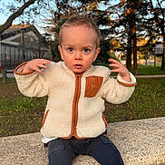Léo participe au concours pour gagner de l'argent avec cette photo : toddler, child, park, bench, jacket, boots, pants, outdoor, trees, grass, sunlight, fall, expression, face, person, young_child, nature, daytime, casual_clothing, curious