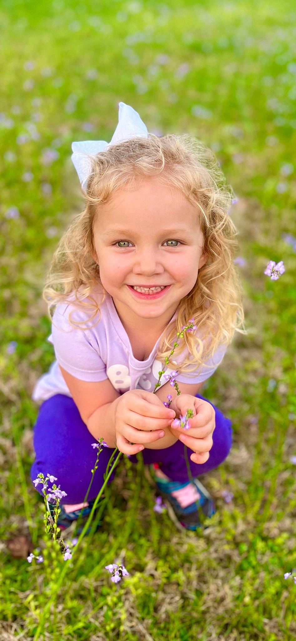 Audrey is registered to the contest to win money with this photo: blond, child, electric_blue, face, fun, gesture, grass, grass_family, grassland, hand, happy, iris, joy, meadow, people_in_nature, person, plant, prairie, purple, smile