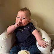 Ralphie joined the competition — help win amazing prizes! baby, infant, child, sitting, thumb_sucking, navy_shirt, jeans, white_chair, orange_pattern, curly_hair, bracelet, indoor, cute, smiling, portrait, young_child, casual_clothing, happy, plush_chair, relaxed