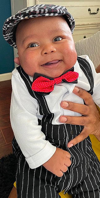Hakeem is registered to the contest to win money with this photo: baby, baby_toddler_clothing, bow_tie, child, collar, drinkware, formal_wear, fun, gesture, happy, headwear, iris, joy, lip, pattern, person, personal_protective_equipment, sleeve, smile, thumb