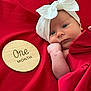 baby, infant, one_month, headband, white_bow, red_blanket, red_background, wooden_plaque, hand, face, portrait, newborn, cute, lying_down, skin, expression, child, closeup, soft, resting