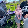 adult, baby, chair, child, daytime, fence, footwear, grass, hand, headband, house, outdoor, person, pink_clothing, relaxation, sky, stroller, sunny, trampoline, tree