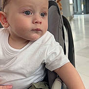 Manaël participe au concours pour gagner de l'argent avec cette photo : toddler, child, baby, car_seat, white_tshirt, green_pants, indoor, curious, portrait, young_child, face, hands, foot, seated, casual_clothing, expression, looking_away, human, person, closeup