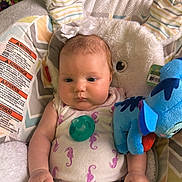 Rose is registered to the contest to win money with this photo: baby, infant, pacifier, plush_toy, bunny_ears, baby_seat, patterned_clothing, white_pants, purple_seahorses, chubby_cheeks, colorful_background, soft_texture, cute, child, indoor, comfort, toy, relaxed, headband, portrait