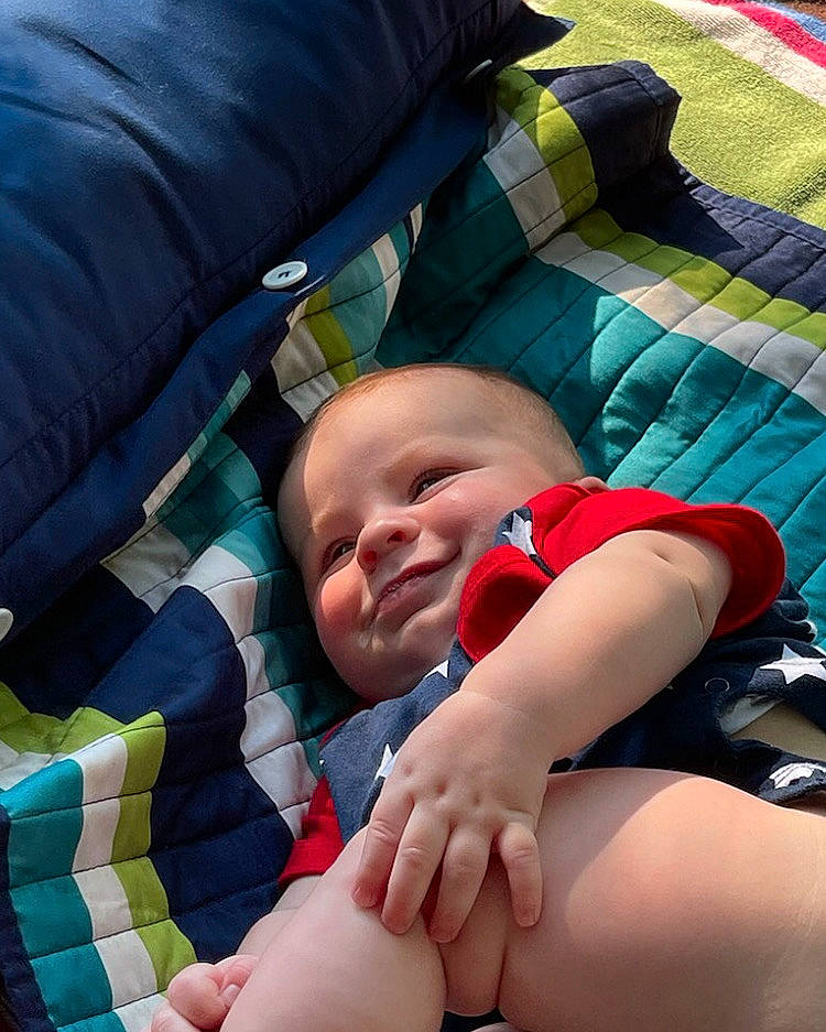 Evander is registered to the contest to win money with this photo: baby, baby_toddler_clothing, child, comfort, couch, finger, foot, fun, grass, knee, lap, leisure, linens, mammal, person, sitting, textile, thigh, thumb, toddler