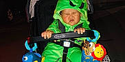 Elijah joined the competition — help win amazing prizes! baby, child, stroller, costume, green, hood, plush_toy, night, outdoor, face, scrunched_face, hand, footwear, toy, person, expression, graco, cute, infant, clothing
