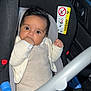 baby, car_seat, infant, child, seat_belt, car_interior, knit_clothing, hand, face, eyes, foot, sitting, safety, cute, indoors, person, car_door, window, black, white