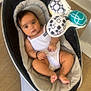 Djanna a rejoint le concours — aidez-le/la à gagner de superbes lots ! baby, infant, baby_rocker, mobile_toy, white_clothing, floor, wood_flooring, indoor, child, looking_at_camera, curious, relaxed, modern_design, toy, black_hair, skin, foot, hand, seat, baby_accessory