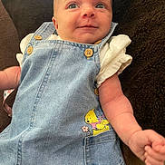 Iris joined the competition — help win amazing prizes! baby, denim_overalls, cartoon_character, pocket, blanket, infant, cute, smile, face, arm, clothing, child, portrait, textile, fabric, button, skin, person, casual_wear, lying_down