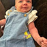 baby, denim_overalls, cartoon_character, pocket, blanket, infant, cute, smile, face, arm, clothing, child, portrait, textile, fabric, button, skin, person, casual_wear, lying_down