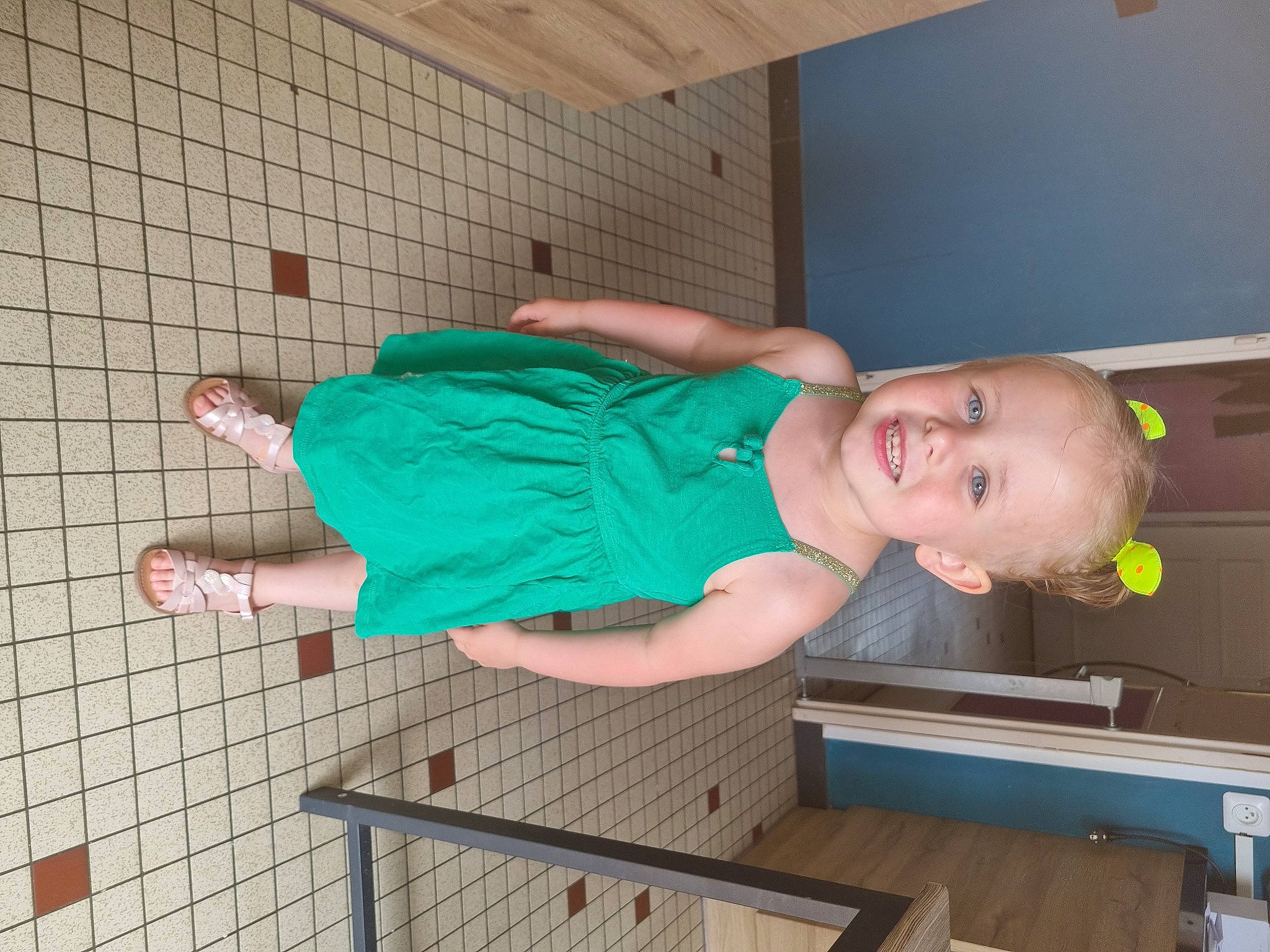 Mathilde participe au concours pour gagner de l'argent avec cette photo : baby, baby_products, baby_safety, baby_toddler_clothing, child, floor, flooring, foot, fun, hardwood, human_leg, joy, knee, pattern, person, room, sandal, sitting, smile, thigh