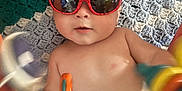 Bohdi is registered to the contest to win money with this photo: baby, sunglasses, toy, crocheted_blanket, child, infant, face, playtime, colorful, cute, smiling, indoors, skin, head, reflection, red, blue, orange, yellow, relaxing
