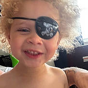 Carter joined the competition — help win amazing prizes! child, toddler, curly_hair, eye_patch, pirate, smile, face, person, bare_shoulders, tattoo, arm, indoor, window, blur, happy, cute, young_child, portrait, close_up, skin