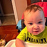 baby, child, blue_eyes, high_chair, green_shirt, indoor, wooden_floor, curious, face, hair, person, table, sitting, home, furniture, expression, cute, infant, toddler, closeup