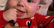 Phoenix joined the competition — help win amazing prizes! baby, child, infant, face, blue_eyes, red_onesie, reindeer_design, high_chair, hand_in_mouth, smile, cheeks, blanket, messy_tray, indoor, closeup, cute, happy, portrait, skin, fingers