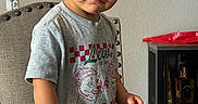 Noah is registered to the contest to win money with this photo: bottle, boy, cabinet, cereal, chair, child, clothing, curious, expression, face, food, furniture, indoor, plate, portrait, short_hair, snack, table, toddler, wall