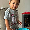 Noah is registered to the contest to win money with this photo: toddler, child, boy, cereal, plate, table, chair, indoor, clothing, short_hair, face, expression, food, snack, cabinet, bottle, furniture, wall, curious, portrait