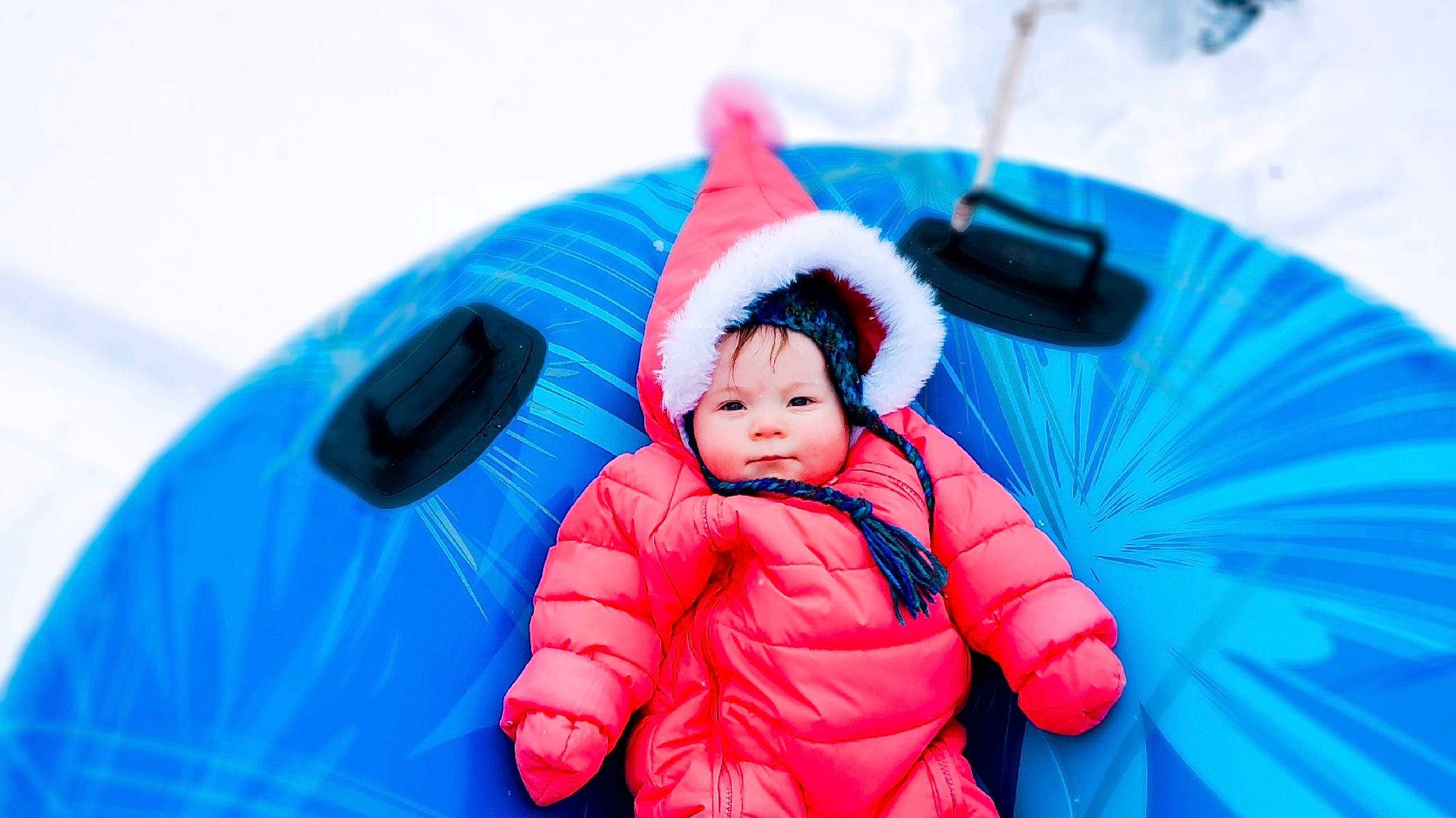 Ryleigh is registered to the contest to win money with this photo: baby, blue, cap, child, electric_blue, event, freezing, fun, grass, happy, headwear, inflatable, jacket, leisure, people_in_nature, person, plant, playing_in_the_snow, recreation, toddler