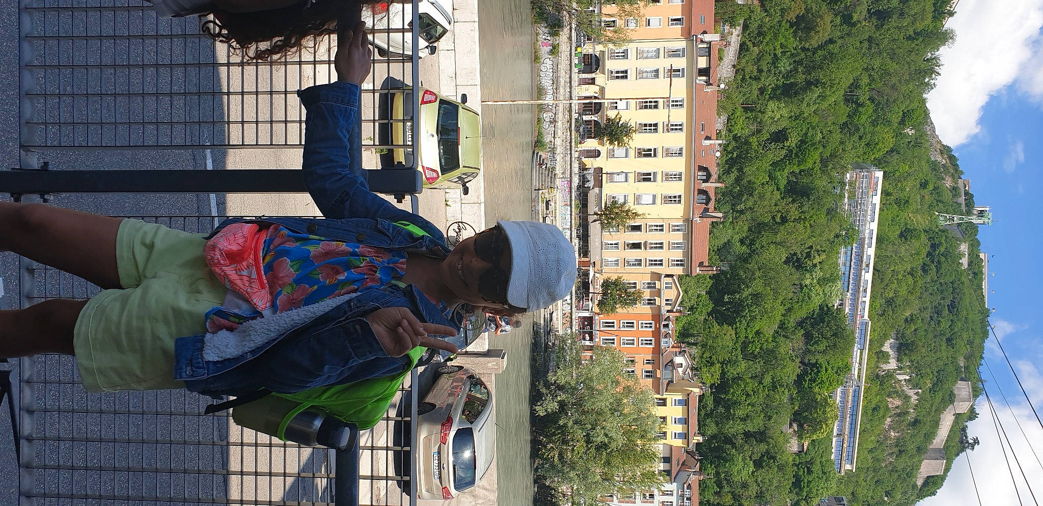 Fatine participe au concours pour gagner de l'argent avec cette photo : building, city, condominium, daytime, facade, hat, headwear, house, human_settlement, infrastructure, joy, line, neighbourhood, person, plant, road, street, street_light, tree, under_exposed