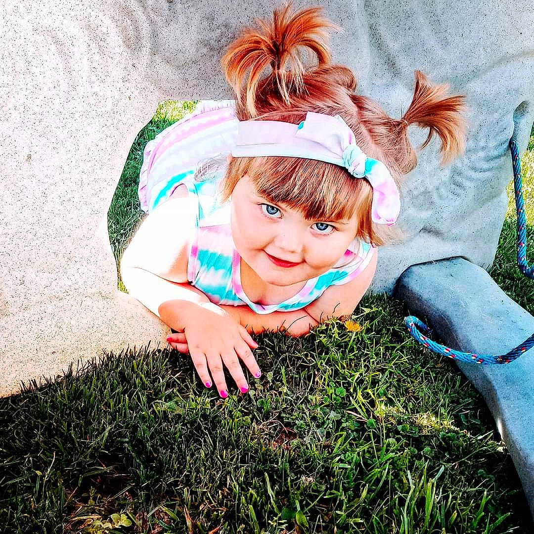 Claudia is registered to the contest to win money with this photo: bangs, brown_hair, child, cool, costume_hat, fashion_accessory, flash_photography, fun, gesture, grass, grassland, happy, headband, headpiece, headwear, interaction, joy, morning, people_in_nature, person