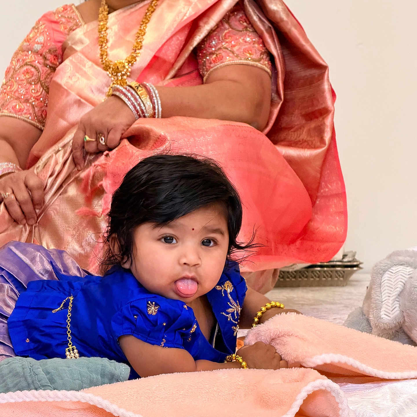 Krithya Repaka is registered to the contest to win money with this photo: baby, blanket, blue_dress, bracelet, candid, child, cute, family, floor, gold, indoor, infant, jewelry, person, portrait, saree, soft_texture, tongue_out, traditional_clothing, woman