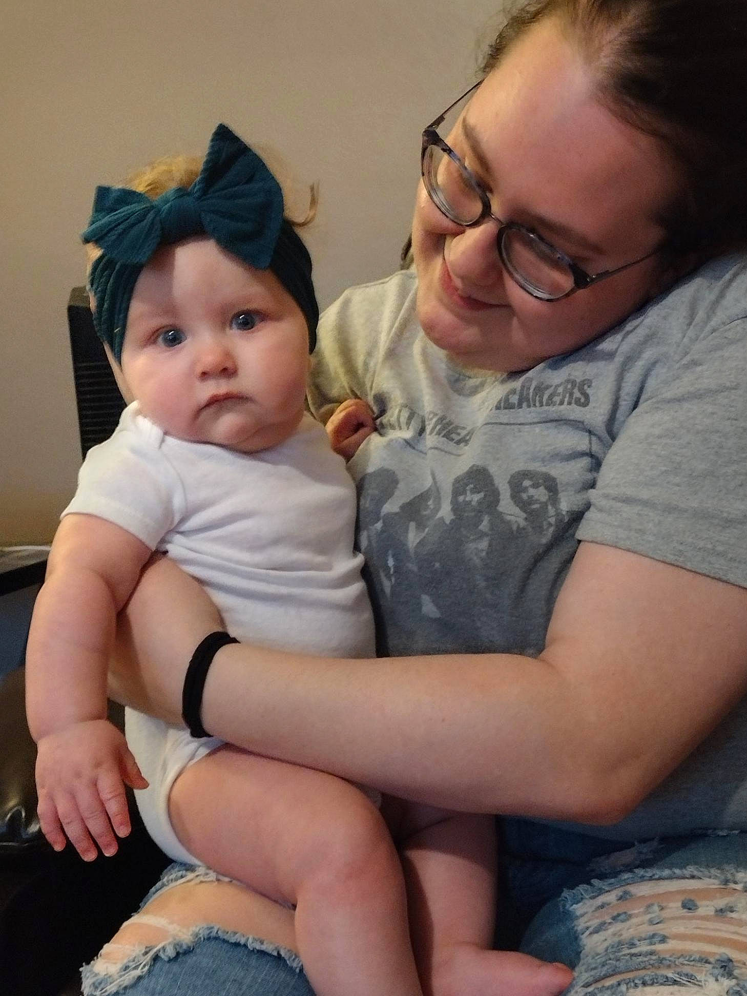 Nora is registered to the contest to win money with this photo: baby, cheek, clothing, comfort, eye, face, facial_expression, glasses, happy, head, headwear, human_body, interaction, iris, lap, mouth, person, skin, smile, thigh