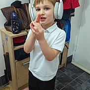 Michael joined the competition — help win amazing prizes! child, boy, headphones, white_shirt, black_pants, indoor, playing, gesture, floor, coat, bag, water_bottle, carpet, shoe, door, cabinet, young, standing, casual_clothing, home