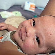 Sebastian is registered to the contest to win money with this photo: baby, infant, face, smile, skin, eyes, clothing, blanket, lying_down, closeup, child, cute, indoors, expression, newborn, person, soft_light, happy, background, portrait