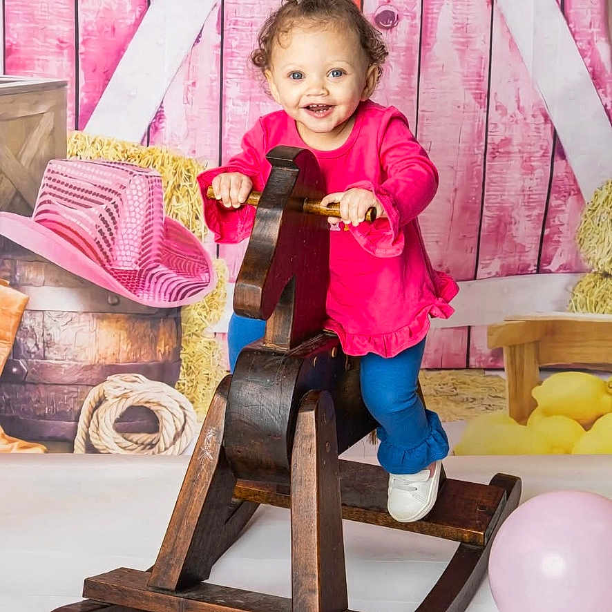 Ellie is registered to the contest to win money with this photo: bed, chair, child, clothing, face, female, furniture, girl, hat, head, highchair, indoors, interiordesign, person, photography, playarea, portrait, rockingchair, toy, wood