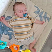 Jules participe au concours pour gagner de l'argent avec cette photo : baby, blanket, child, colorful_toys, comfort, crib, cute, face, indoor, infant, pacifier, peaceful, person, playful, resting, shorts, sleeping, soft_bedding, striped_shirt, toy