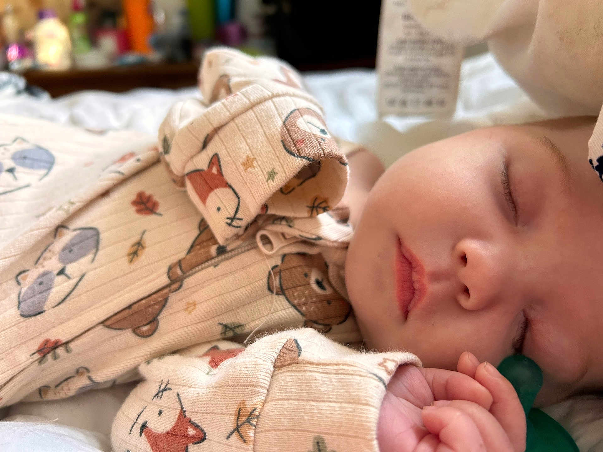 Nayeli is registered to the contest to win money with this photo: baby, sleeping, pacifier, onesie, animal_print, cozy, closeup, infant, peaceful, soft_light, hand, face, child, cute, bed, fabric, pattern, napping, skin, indoors