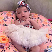 Izzybella is registered to the contest to win money with this photo: baby, child, clothing, comfort, cushion, cute, expression, feet, flower_pattern, hands, headband, indoor, infant, person, pink, portrait, sitting, soft, tutu, white